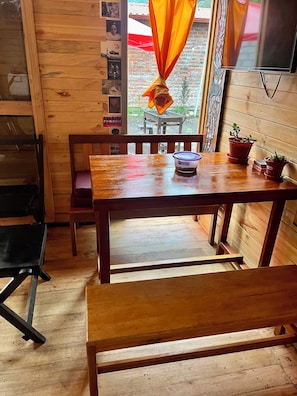 A wooden interior with a table, chairs, and potted plants.
