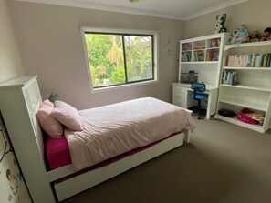 Une chambre à coucher avec un lit, une fenêtre, un bureau et une bibliothèque.