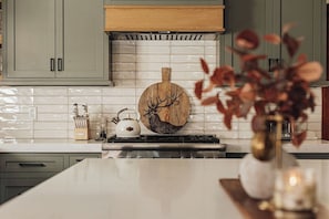 A kitchen with a white countertop, a stove, and a decorative wooden board with a deer design. - Central AC, Walk to Lake, Hot Tub, King Beds (Lake Arrowhead)