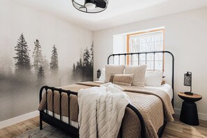 A bedroom with a bed, a window, a wall mural, and a bedside table. - Central AC, Walk to Lake, Hot Tub, King Beds (Lake Arrowhead)