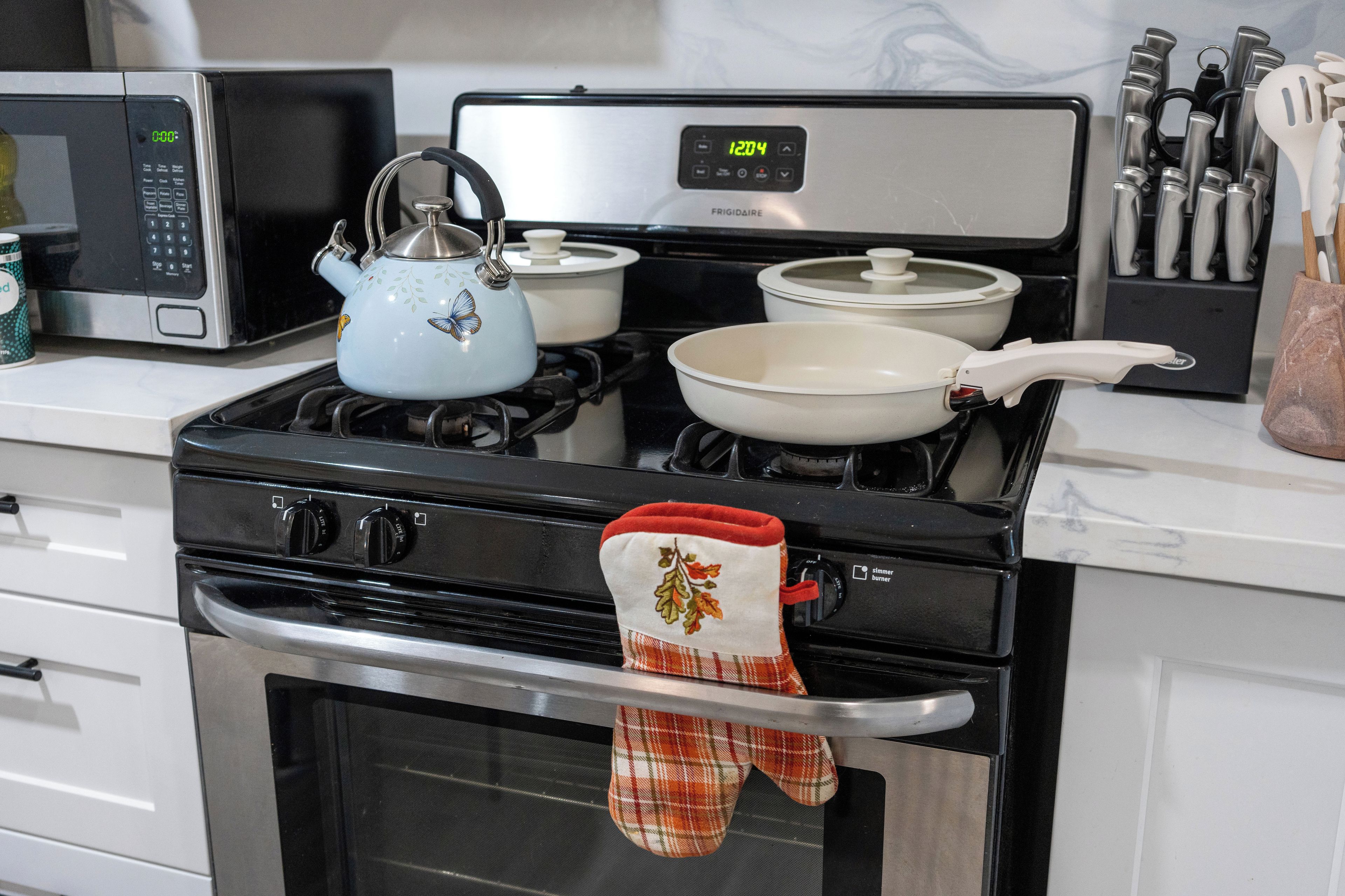 Eine Küche mit Mikrowelle, Herd, Töpfen und Wasserkocher.