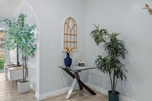 Ein modernes Interieur mit Glastisch, Topfpflanzen und einem dekorativen Fenster.