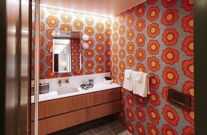 A bathroom with a double sink, a mirror, a towel rack, and a patterned floral wallpaper. - Boutique King Suite with Private Kitchen in East Austin (Austin)