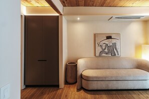 A modern interior with a wooden ceiling, a beige sofa, a framed artwork, and a tall vase. - (Austin)