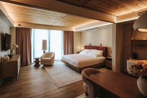 A hotel room with a bed, a desk, a chair, a lamp, and a TV on the wall. - Boutique King Suite with Private Kitchen in East Austin (Austin)