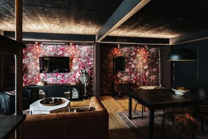 A modern living room with a sofa, a dining table, and a TV mounted on the wall. - Boutique King Suite with Private Kitchen in East Austin (Austin)