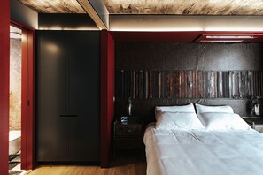 A bedroom with a large bed, a wooden ceiling, a dark wall with a leather headboard, and a red door. - Boutique King Suite with Private Kitchen in East Austin (Austin)