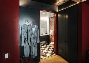 A hallway with a checkered floor, a wooden bench, and a door leading to a bathroom with a marble wall and a toilet. - Boutique King Suite with Private Kitchen in East Austin (Austin)