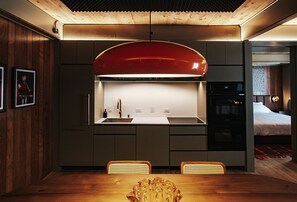 A modern kitchen with a red overhead hood, a sink, and a dining area with a wooden table and chairs. - Music-Inspired King Suite with Private Kitchen in East Austin (Austin)