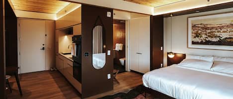 A modern bedroom with a large bed, a wooden ceiling, a built-in wardrobe, and a painting on the wall.