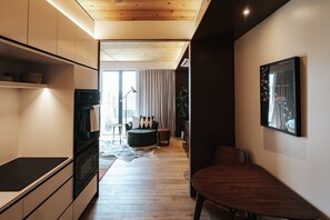 A modern kitchen with built-in appliances, a dining area with a wooden table, and a living space with a sofa and a plant. - Boutique King Studio with Private Kitchen in East Austin (Austin)