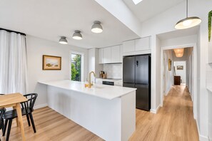 A modern kitchen with a central island, white cabinetry, and a stainless steel refrigerator. - Sundrift Escape Lauderdale Beach and Dining Close By (Lauderdale)