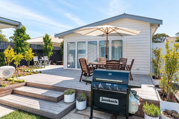Une terrasse avec un barbecue, du mobilier d’extérieur et un espace salon abrité.