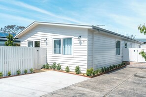 Une maison mobile de plain-pied, avec une façade blanche, un porche à l’avant et un petit jardin.