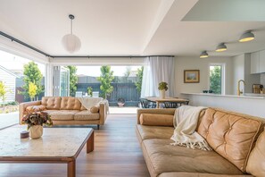 A spacious living room with leather sofas, a coffee table, and a dining area with a table and chairs. - Sundrift Escape Lauderdale Beach and Dining Close By (Lauderdale)