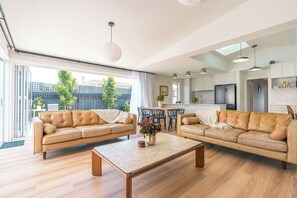 A modern living room with two leather sofas, a wooden coffee table, and a dining area with chairs. - Sundrift Escape Lauderdale Beach and Dining Close By (Lauderdale)