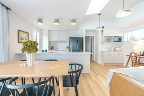 Une cuisine moderne avec des meubles blancs, un îlot central et des luminaires suspendus.