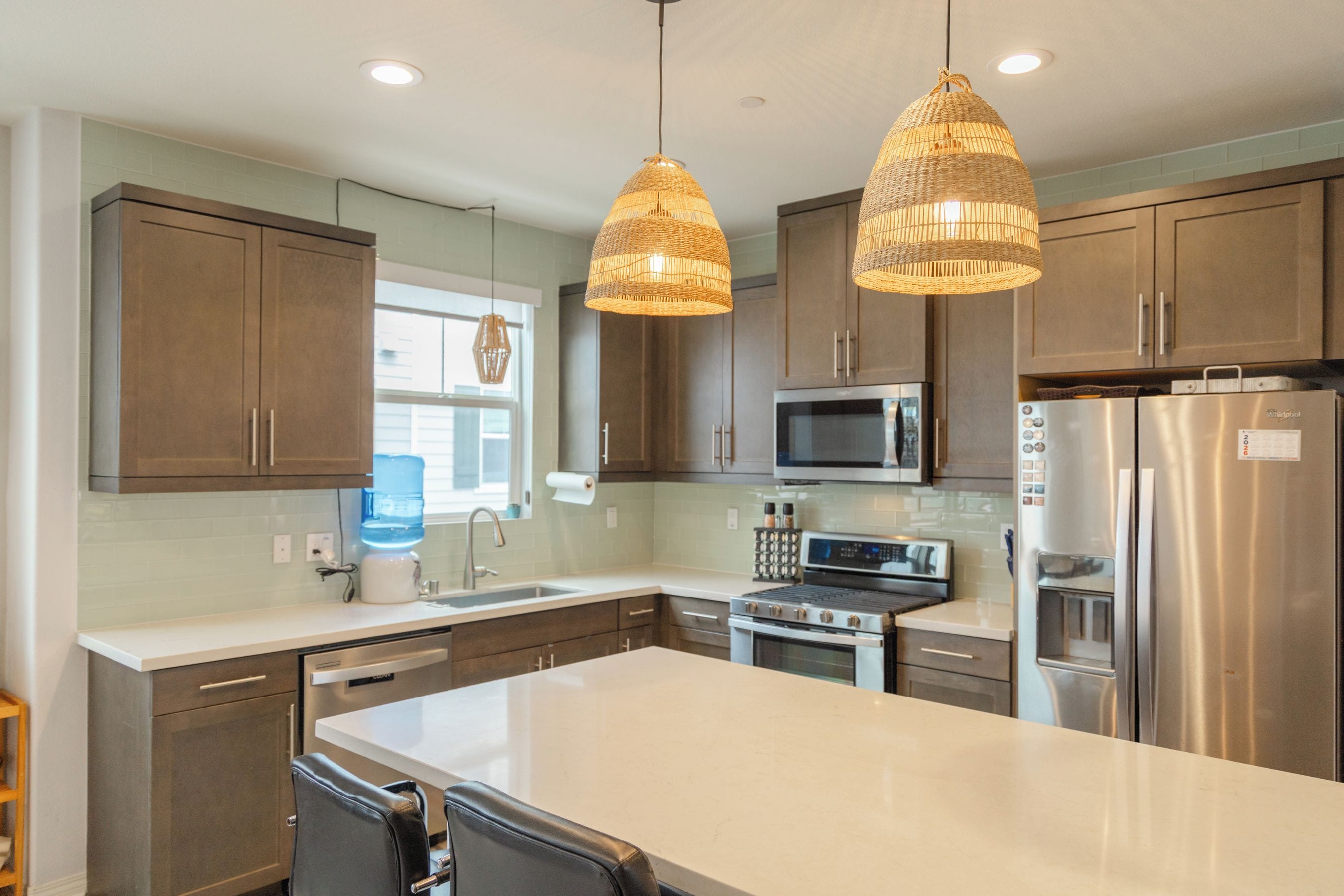 A modern kitchen with stainless steel appliances, a large island, and pendant lighting.