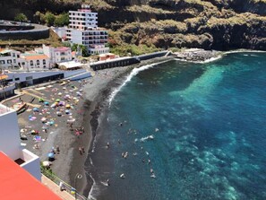 A coastal beach with clear turquoise waters, a rocky shoreline, and a pier extending into the sea. - TenoHomes Villa SAYAN, Private Pool & Teide Views (Icod de los Vinos)