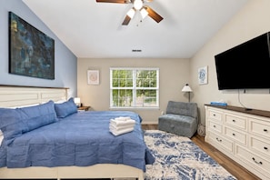 A bedroom with a bed, a television, a window with blinds, a chair, and a dresser. - Cozy Waterview Cottage | Sunroom • Waterfront (Brownsburg)