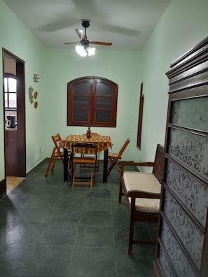 A dining area with a table and chairs, a ceiling fan, a window, and a door. - House in Itauna with 3 bedrooms, 1 suite, balcony, near the beach, parking for 3 cars, green area. (Saquarema)