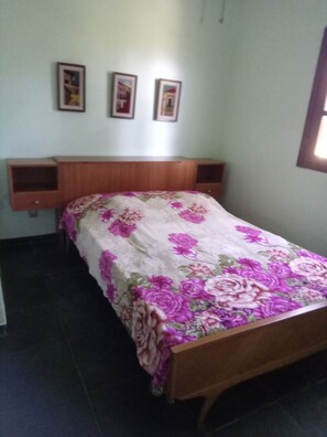 A bedroom with a bed, a wooden headboard, and a wall-mounted shelf. - House in Itauna with 3 bedrooms, 1 suite, balcony, near the beach, parking for 3 cars, green area. (Saquarema)