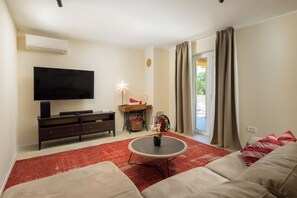 A living room with a flat-screen TV, a coffee table, a sofa, a small table with a lamp, and a sliding glass door leading outside. - Villa Marifran (Istria - Rakalj) (Rakalj)