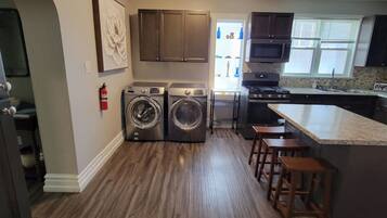 A laundry area with two washing machines, a microwave, and a stove.