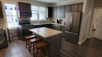 A modern kitchen with a central island, stainless steel appliances, and wooden flooring.