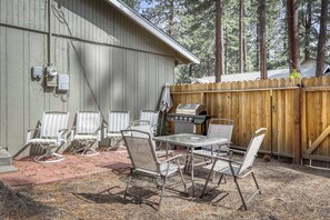 Eine Terrasse mit Grill, Stühlen und einem Tisch.
