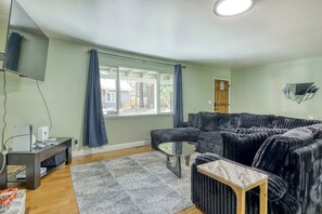 A living room with a sectional sofa, a flat-screen TV, a coffee table, and a window with curtains. - Knox & Pine  3BR Tahoe Home Fireplace & Garage (South Lake Tahoe)