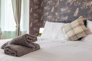A neatly made bed with white linens and a folded gray towel on the left. - Greater Manchester | Whole home | 5-Bedroom | Sleeps 8 | (Tyldesley)