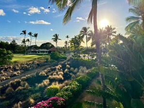 A tropical landscape with palm trees, a golf course, and a building with a red roof. - new Luxury Ocean View Penthouse (Waikoloa Village)