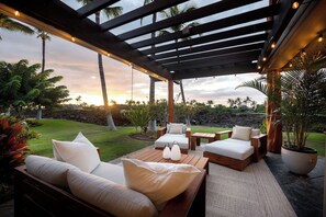 Eine Terrassengruppe im Freien mit Holzmöbeln, einer Pergola und Blick auf den Sonnenuntergang.