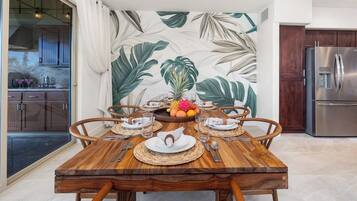 A dining area with a wooden table set for four, surrounded by chairs.