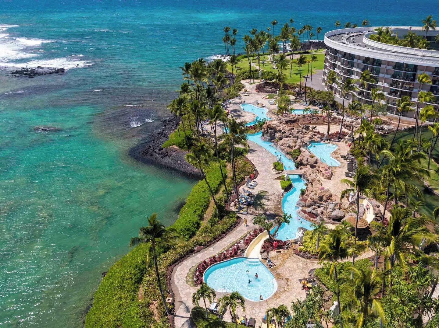 Un complex turístic amb una zona de piscines espaiosa, una piscina separada i vista a l'oceà.