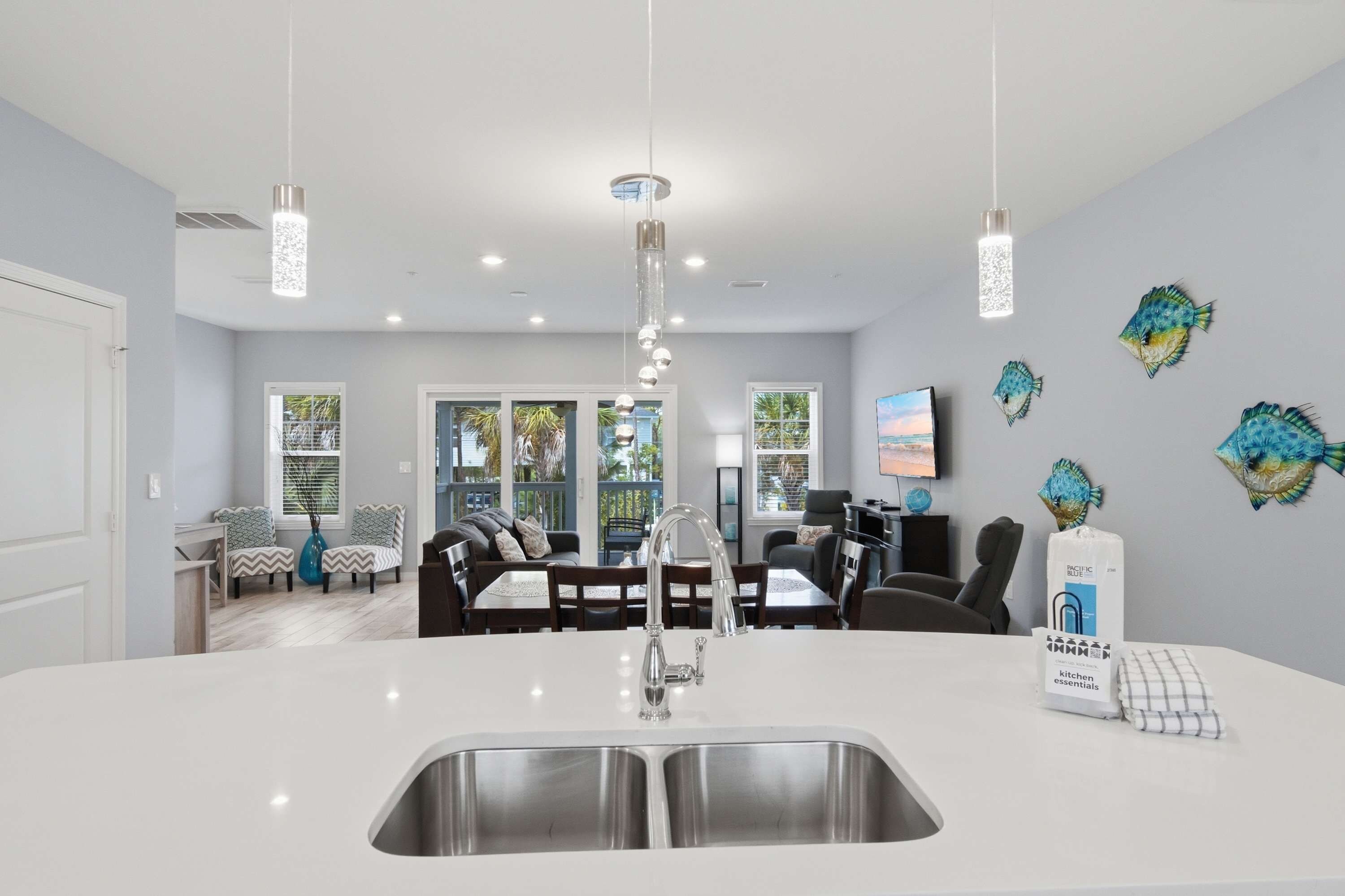 Una cocina moderna con una isla central, pileta de acero inoxidable e iluminación colgante.