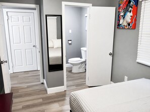A bedroom with a bed, a bathroom with a toilet, and a door leading to another room. - Peaceful 3BR Corner Home w/ Large Yard & Patio Kid and Pet Friendly (Sacramento)