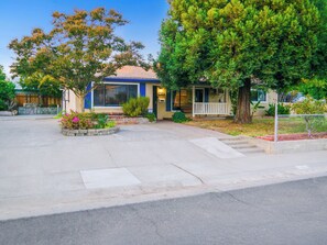 A residential building with a front porch, a driveway, and a landscaped garden. - Peaceful 3BR Corner Home w/ Large Yard & Patio Kid and Pet Friendly (Sacramento)