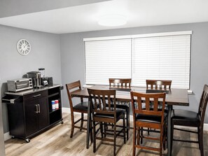 A dining area with a table and chairs, a kitchen area with appliances, and a window with blinds. - Peaceful 3BR Corner Home w/ Large Yard & Patio Kid and Pet Friendly (Sacramento)