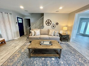 A living room with a sofa, coffee table, and decorative wall elements. - Cozy Lake House 1 - Lakefront Retreat with Private Dock & Fire Pit (Macon)