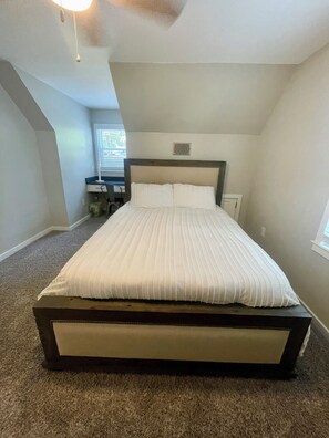 A bedroom with a bed, a nightstand, a lamp, and a window. - Cozy Lake House 1 - Lakefront Retreat with Private Dock & Fire Pit (Macon)