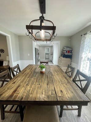 Ein Esszimmer mit Holztisch, Stühlen, einer Hängeleuchte und einem Blumentopf.