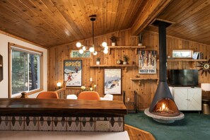 A cozy cabin interior with a wooden interior, a fireplace, a bar area, and a television. - Sierra Chalet - Celebrity Vacation Homes (Big Bear Lake)