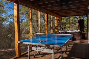 Ein Tischtennistisch im Freien mit Whirlpool und Holzterrasse.