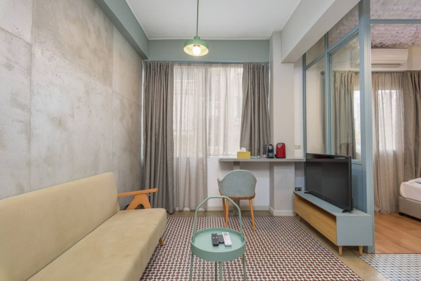 Una sala moderna con un sofá, una mesita, una silla, un televisor y un escritorio con una computadora.