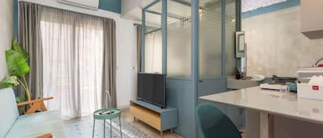 Un salon moderne comprenant un canapé, un téléviseur et un coin repas avec des chaises et une table.