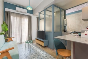 Una sala moderna con sofá, televisor y un comedor con sillas y mesa.
