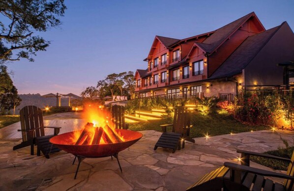 A large building with multiple windows and a fire pit in the foreground. - Vrbo Property (Gramado)