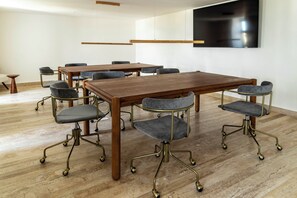 A conference room with a large wooden table, grey upholstered chairs with metal legs, and a black screen mounted on the wall. - Brand-New 2BR at Ceiba25 - Rooftop Infinity Pool, Near Beach & 5th Ave (Playa del Carmen)
